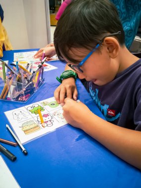 Kuala Lumpur, Malezya - Kasım 2019: Geri dönüşümlü plastik bir konteynır örtüsüne çizim yapan genç bir çocuğun yüksek açılı yakın çekimi. Anahtarlık yapıyorum..