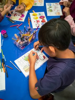 Kuala Lumpur, Malezya - Kasım 2019: Geri dönüşümlü plastik bir konteynır örtüsüne çizim yapan genç bir çocuğun yüksek açılı yakın çekimi. Anahtarlık yapıyorum..