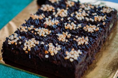 Tahta arka planda, üzerinde badem uçları, ev yapımı fırın ve tatlı olan plastik bir kapta çikolatalı brownie.