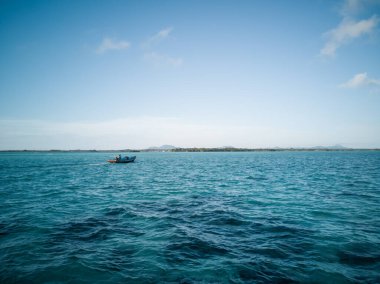 Sürat teknesi dalgalı denizde hızla ilerliyor. Çok güzel bir gün. Arka planda mavi suyun üzerinden geçen hızlı gemi mavi gökyüzünü ve adayı gösteriyor..