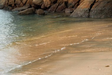 Kumsalın arka planında köpüklü yumuşak dalgalar.