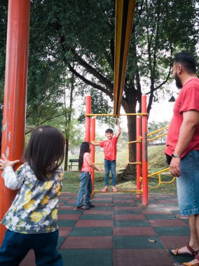 Parktaki maymun parmaklıklarında oynayan Asyalı baba ve çocuklar.. 