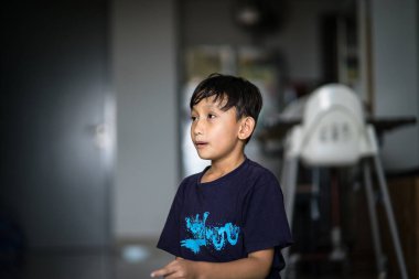 Siyah gömlekli çocuk odada.