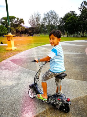 Parkta scooter süren küçük bir çocuk.
