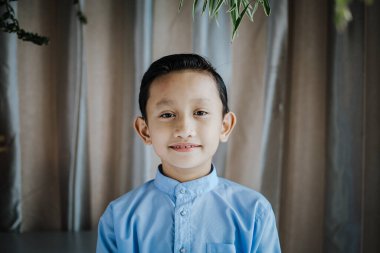 Güney Asyalı yakışıklı çocuğun portresi ayakta ve gülümsüyor. Malezyalılar.