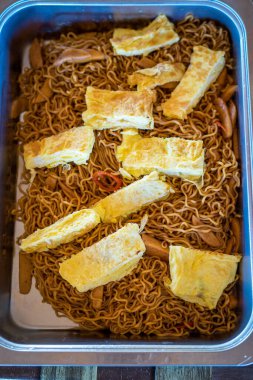 Omlet ve sebzeli Lezzetli Kızarmış Erişte (Indomie Goreng). Yemek konteynırında servis edildi..
