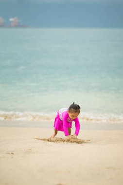 Sahilde oynayan küçük Asyalı kız. Tatil ve rahatlama konsepti..