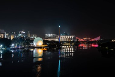 Renkli camili gece sahnesi, sıcak hava balonu ve Putrajaya, Malezya 'daki nehir yansımalı köprü..