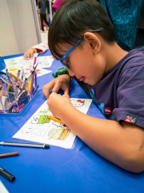 Kuala Lumpur, Malezya - Kasım 2019: Geri dönüşümlü plastik bir konteynır örtüsüne çizim yapan genç bir çocuğun yüksek açılı yakın çekimi. Anahtarlık yapıyorum..