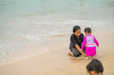 Genç Asyalı çocuklar sahilde oynuyorlar. Tatil ve rahatlama kavramı.