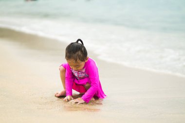 Sahilde oynayan küçük Asyalı kız. Tatil ve rahatlama konsepti..
