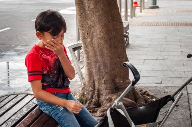 Asyalı ağabey yol kenarında küçük kız kardeşiyle oturup bekliyor..
