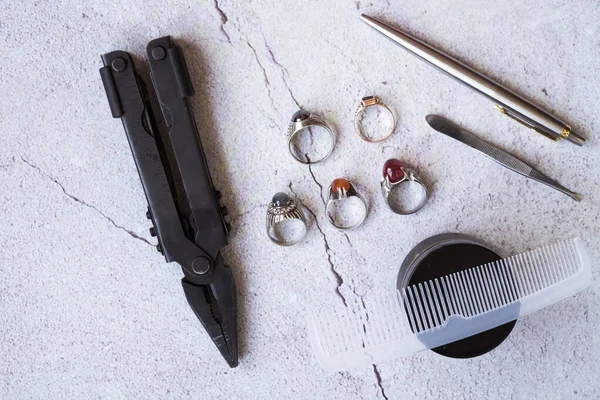 Şık erkek yüzükleri, kalem, aletler, mendil, poz ve tımar için parfüm. Beton arka planda metroseksüel sezaryenler. Şehir kompozisyonu. Üst görünüm.