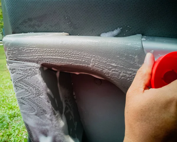 Dry cleaning the car interior with special foam. Car care concept. Car detailing. Cleaning driver seat using professional tools and cleaners