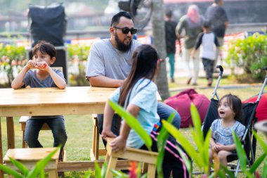 PUTRAJAYA, MALAYSIA - 6 Eylül 2019: Malezya 'nın Putrajaya kentindeki Royal Floria Putrajaya bahçesinde boş vakitlerinde oturan yerel aile.