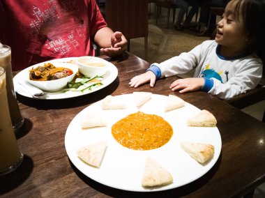 Asyalı baba ve bebek Arap restoranında akşam yemeği.