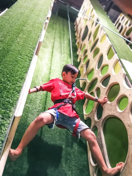 Boy Climbing Wall Wearing Climbing Equipment Indoor Playground Low Angle — Stock fotografie