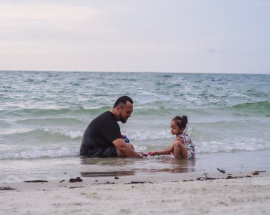 Baba ve kızı kumsalda oynuyorlar..