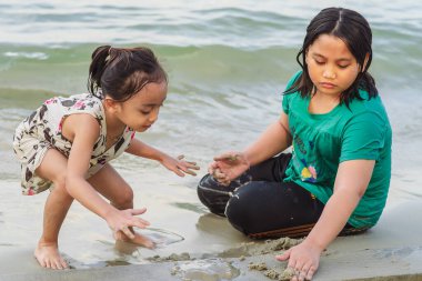 Çocuklar birlikte kum oynuyorlar. Sahilde oynayan Asyalı küçük çocuklar..