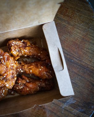 Kore usulü kızarmış tavuk kanatları ve paket servis kutusunda davullar. Geleneksel Asya tarifi.