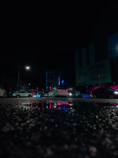 反射して道路上の雨の夜 水溜りからの眺めを閉じます サイバーパンクのテーマ — ストック写真