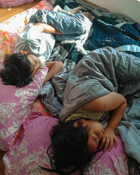 Siblings sleep in bed together during the day the time.