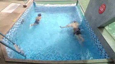 Playful father and son swimming underwater in private pool villa. A fun weekend spent together. Family concept