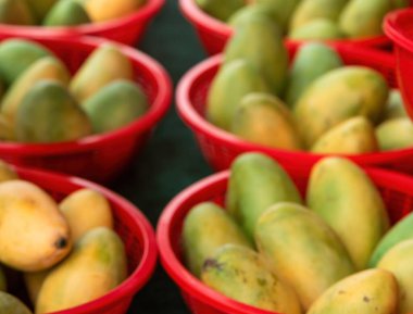 Tezgahtaki kırmızı sepetlerde taze mangoların bulanık fotoğrafı..