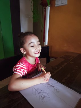 Little kid girl smiling while drawing at home creativity development.