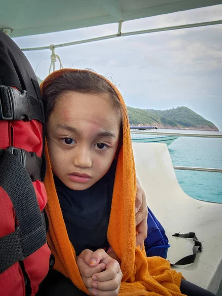 LIttle girl is shivering from cold being on the boat at the sea.