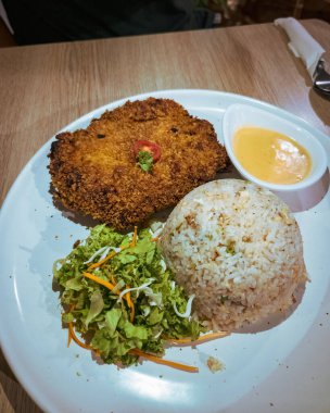 Kızarmış pilav ve salatayla birlikte gelen çıtır tavuk pirzolası..