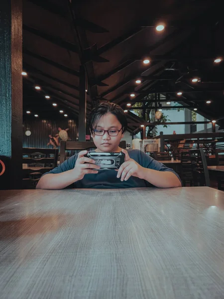 Jovem Adolescente Usando Óculos Sentado Mesa Está Usando Telefone Celular — Fotografia de Stock
