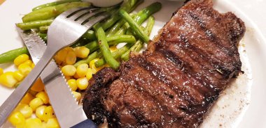 Dünyanın en iyi yemeklerini yemenin sevinci yanında patates püresi, mantar sosu ve tatlı mısırla birlikte beyaz tabakta servis edilen yeşil fasulye.