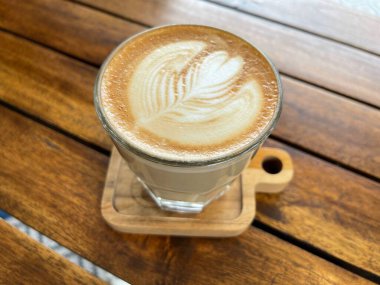 Ahşap arka planda latte sanatıyla birlikte güzel bir fincan kapuçino.