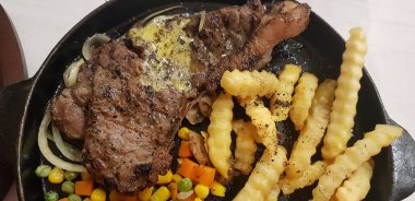 The best food in the world beef steak along with fried potatoes with delicious mushroom sauce and salad and spaghetti plated in beautiful black plate