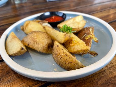 Baked potato wedges with shredded onion and herbs and tomato sauce platted homemade organic vegetable vegan vegetarian potato wedges snack food meal