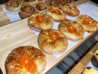 Lines of fresh baked sweet puff pastry stuffed with apricot and peach jelly, super delicious warm fresh buttery sweet puff pastry stuffed with apricot and peach, French and American baked pastries are enjoyed world wide on bakery shop, tasty multiple