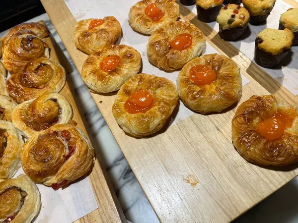 Lines of fresh baked sweet puff pastry stuffed with apricot and peach jelly, super delicious warm fresh buttery sweet puff pastry stuffed with apricot and peach, French and American baked pastries are enjoyed world wide on bakery shop, tasty multiple