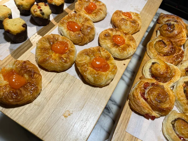 Lines of fresh baked sweet puff pastry stuffed with apricot and peach jelly, super delicious warm fresh buttery sweet puff pastry stuffed with apricot and peach, French and American baked pastries are enjoyed world wide on bakery shop, tasty multiple