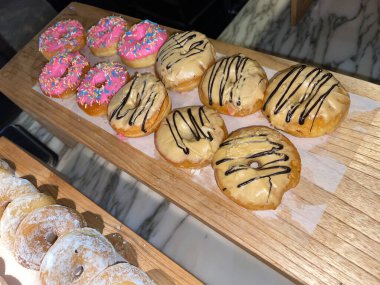 Lines of fresh delicious donuts on bakery shop, tasty multiple donuts, Selective focus donuts with various topping