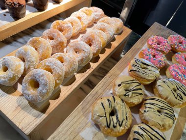 Lines of fresh delicious donuts on bakery shop, tasty multiple donuts, Selective focus donuts with various topping