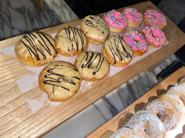 Lines of fresh delicious donuts on bakery shop, tasty multiple donuts, Selective focus donuts with various topping