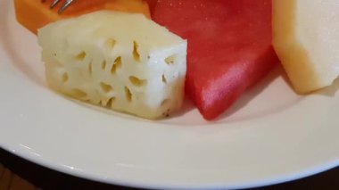 Beyaz tabakta servis edilen papaya, kavun, ananas ve karpuz ile taze ve sulu meyve salatası yemek sağlıklı bir kahvaltıdır.