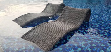 Lüks spa merkezindeki yüzme havuzunda mavi havuz kenarındaki güverte sandalyesini gevşetin ya da aile yaz tatilinde Coronavirus salgını sonrası villa turizmi krizi.