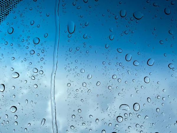 Water droplets perspective through glass surface against blue sky good for multimedia content backgrounds