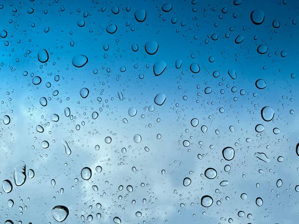 Water droplets perspective through glass surface against blue sky good for multimedia content backgrounds