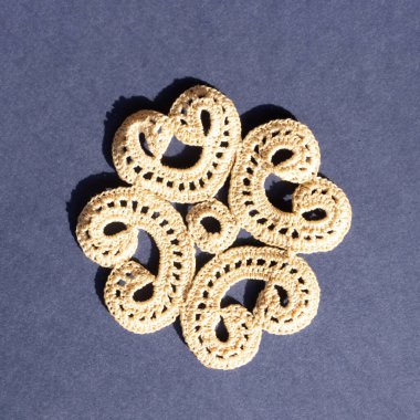 Handmade crochet lace in beige for placemats on a royal blue background. Flat lay.