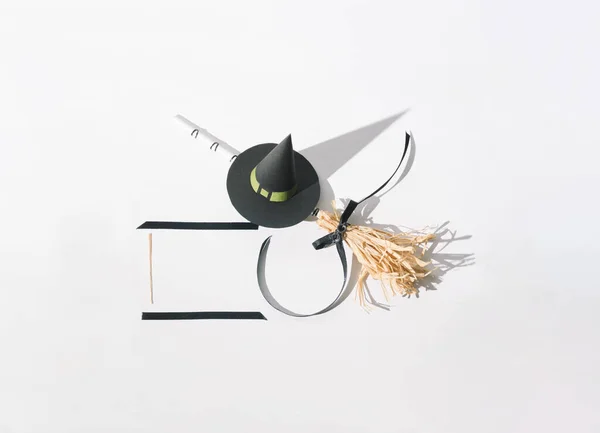 A witch\'s hat and a witch\'s broom for Halloween with a shadow in the background. Minimal holiday celebration horror concept.