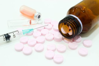 Bir şişe tablet, pembe tablet, 3 ml plastik şırınga, beyaz arka planda izole edilmiş ilaç şişesi ve ampulü