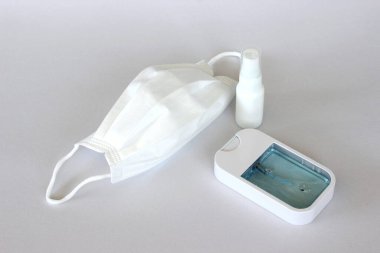 Covid-19 kavramının önlenmesi: Beyaz arkaplanda maske ve alkol spreyi